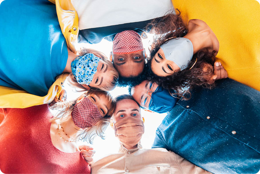 Multiracial group of friends wearing protective face masks taking a selfie - New normal friendship concept with young people looking down at camera and laughing - Bright filter 