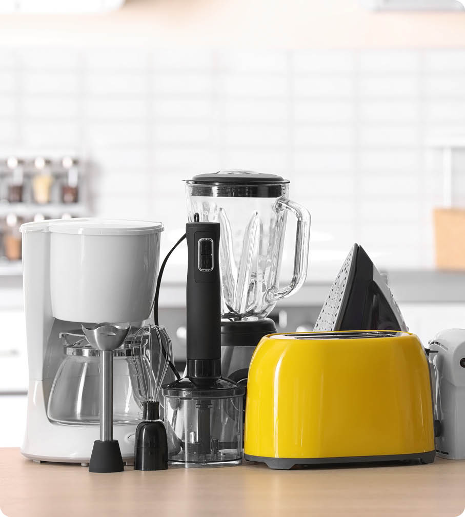 Household and kitchen appliances on table against blurred background 